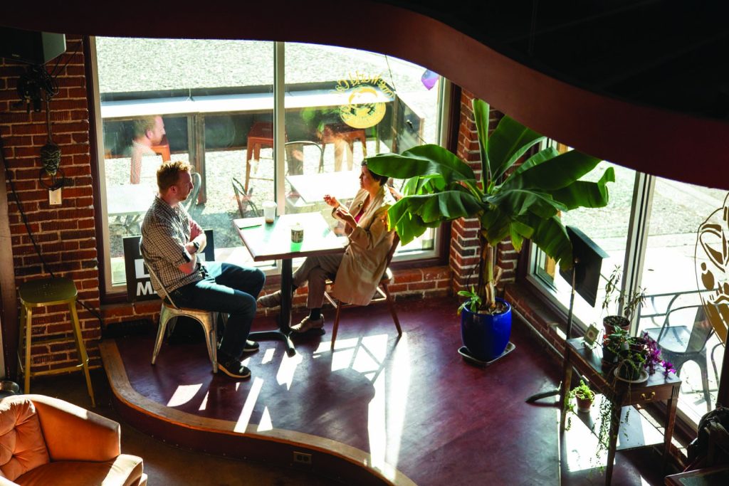 Overhead view of two people at a small window table of a coffee shop